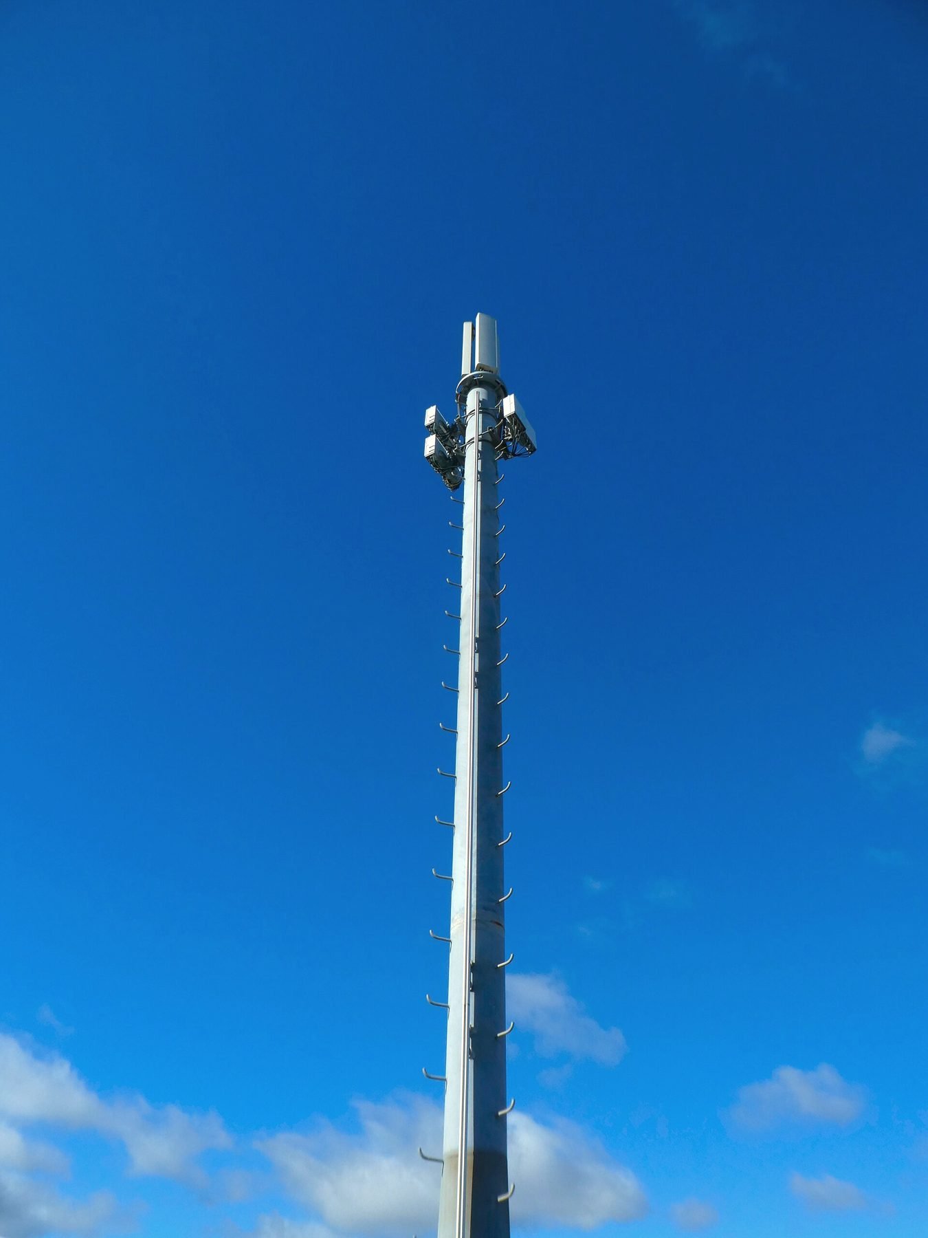 A tall monopole communications tower against a blue sky.