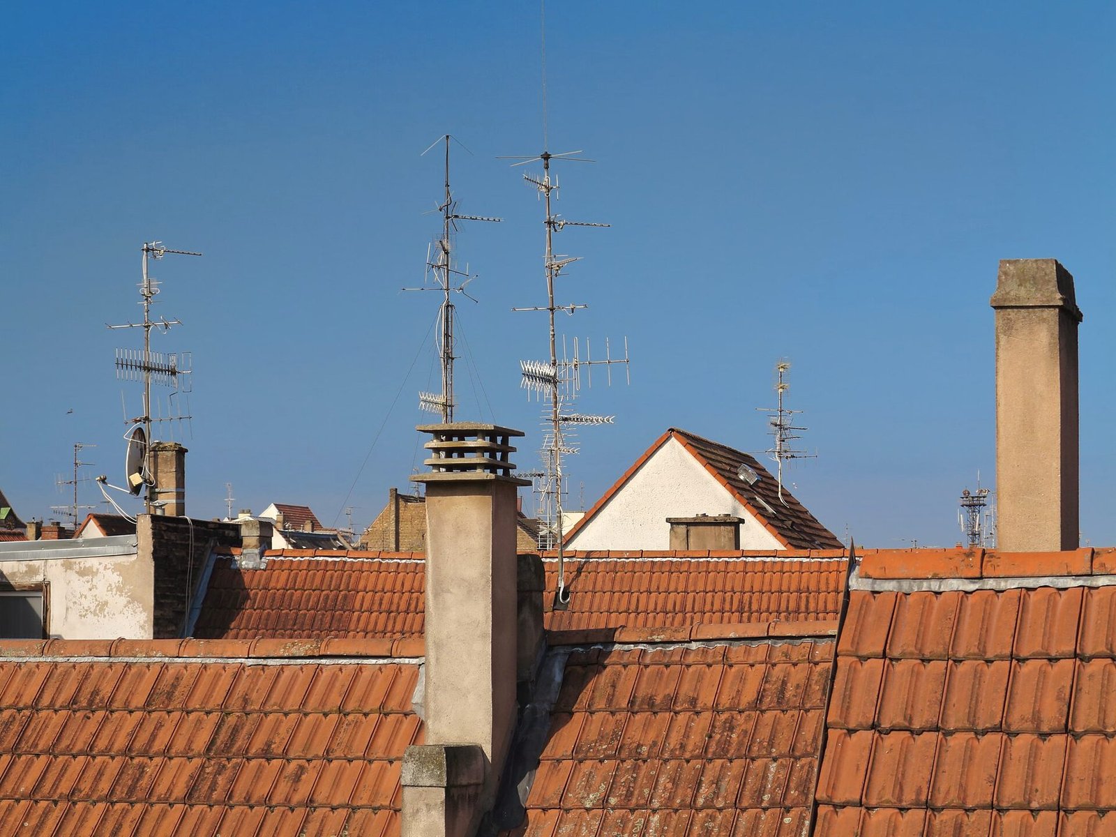 A cluster of antennas rising above a tiled rooftop.