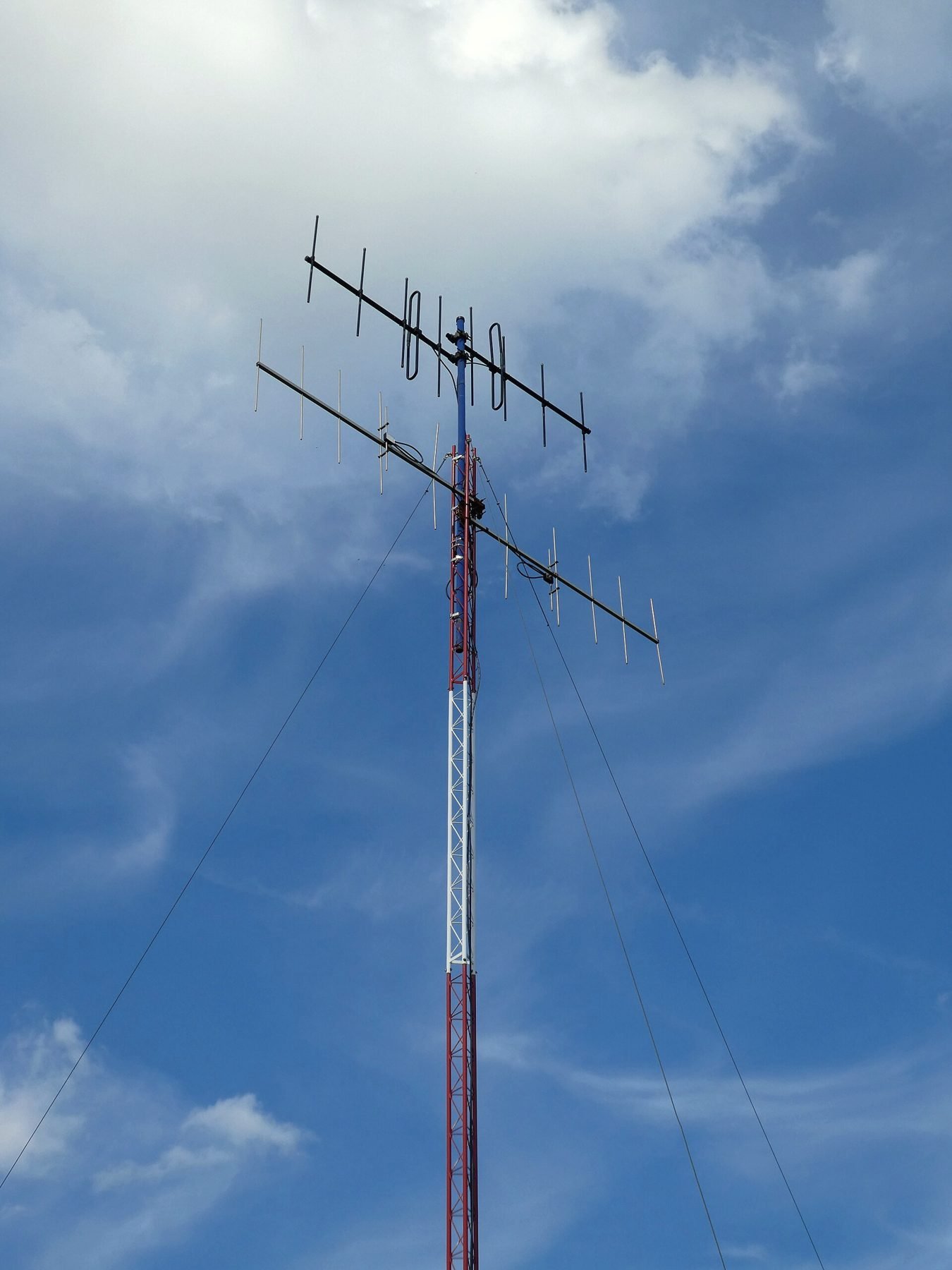 A directional yagi antenna mounted on a slim mast against the sky.
